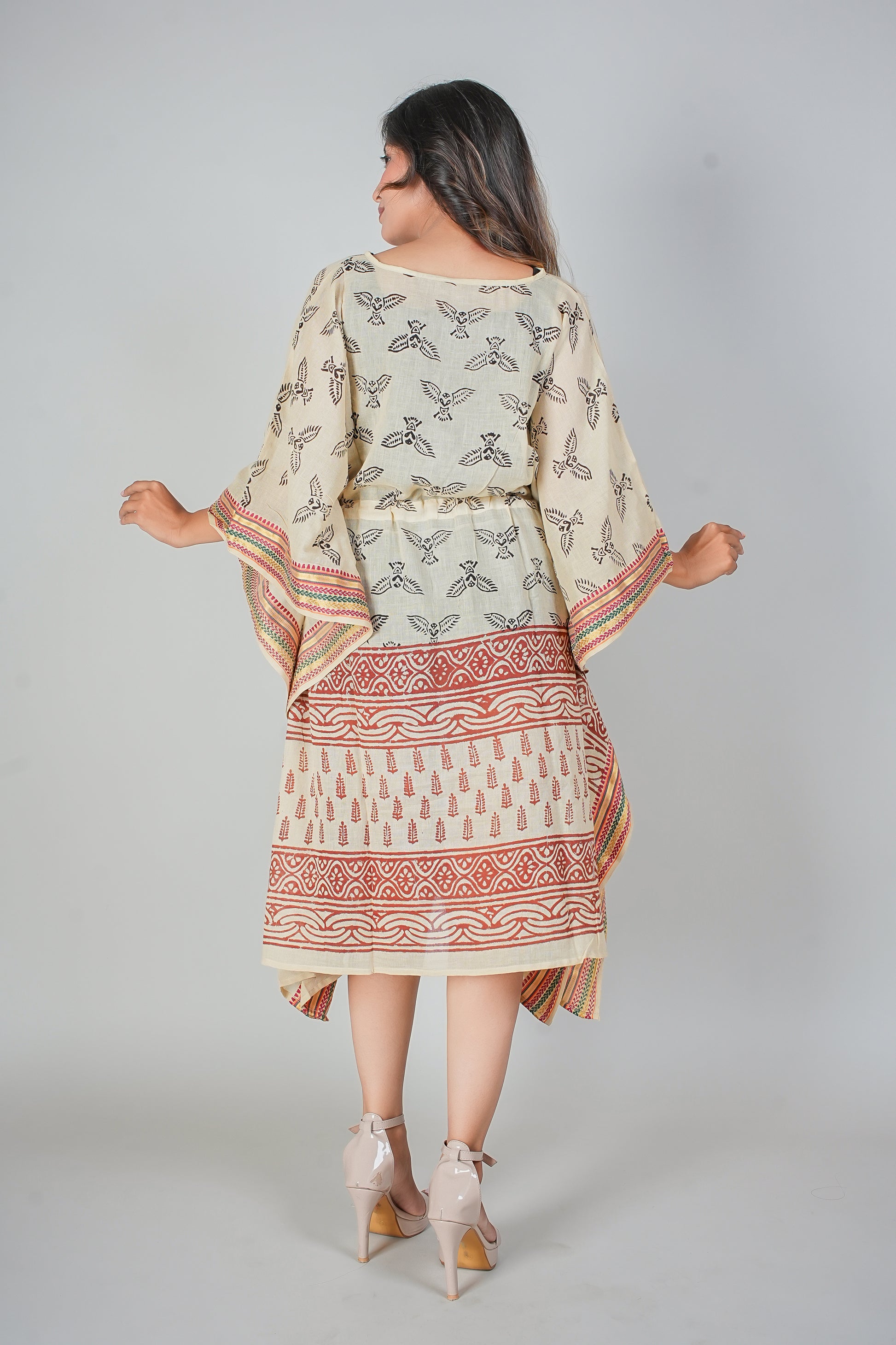 Woman wearing a patterned kaftan dress with a plain background