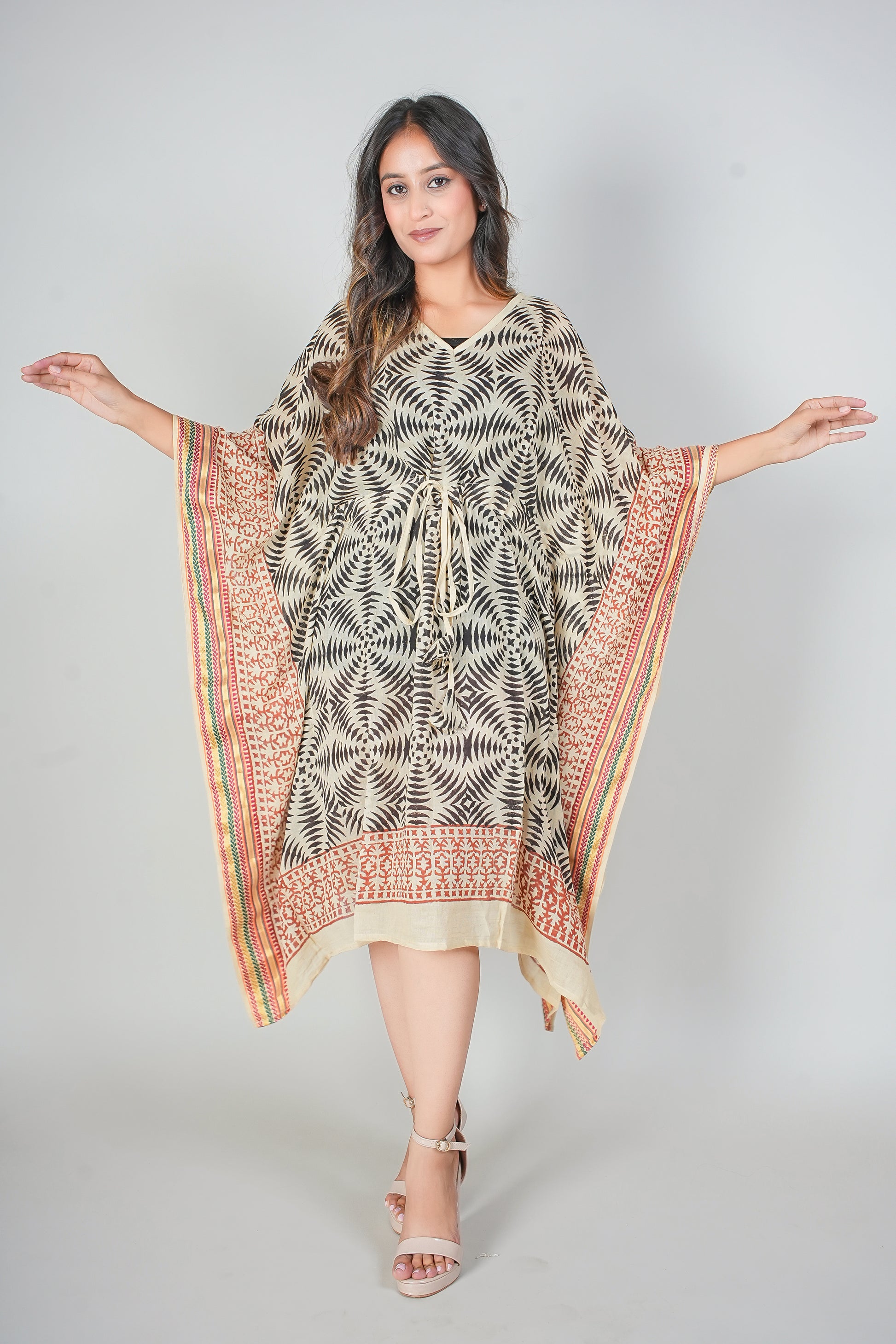 Woman wearing a patterned caftan dress with a plain background