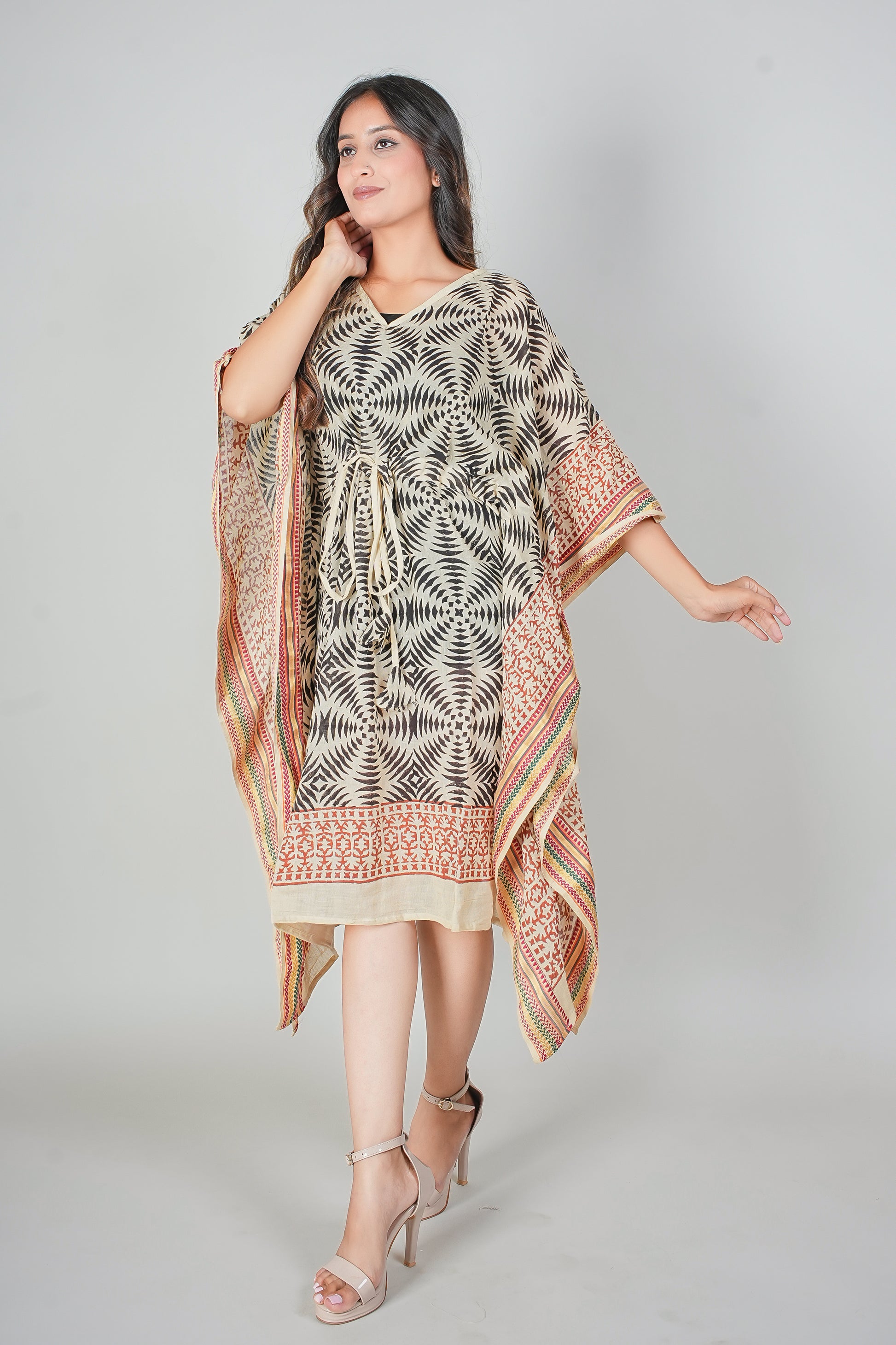 Woman wearing a patterned kaftan dress with a matching shawl on a plain background
