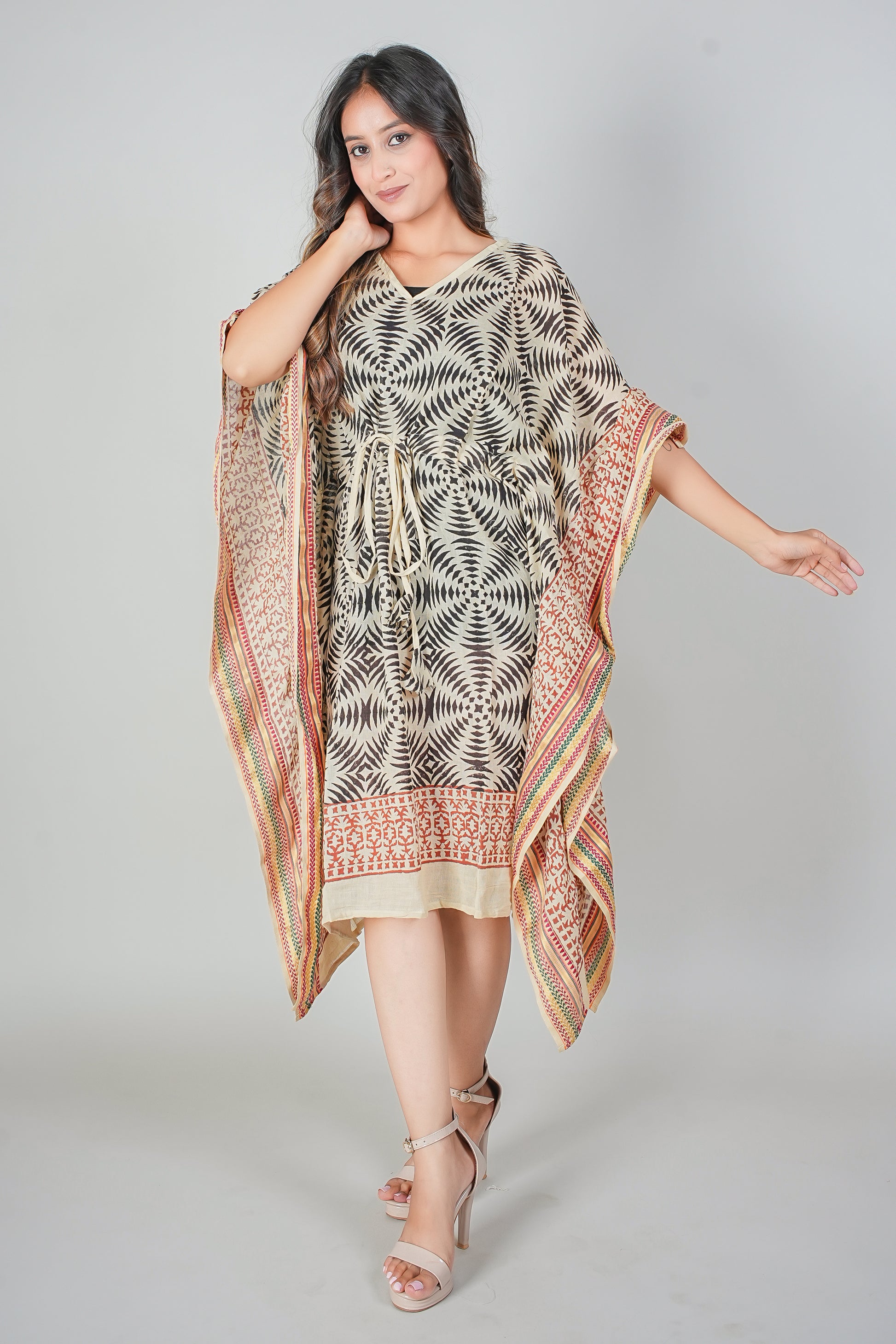 Woman wearing a patterned kaftan dress with a matching shawl on a gray background