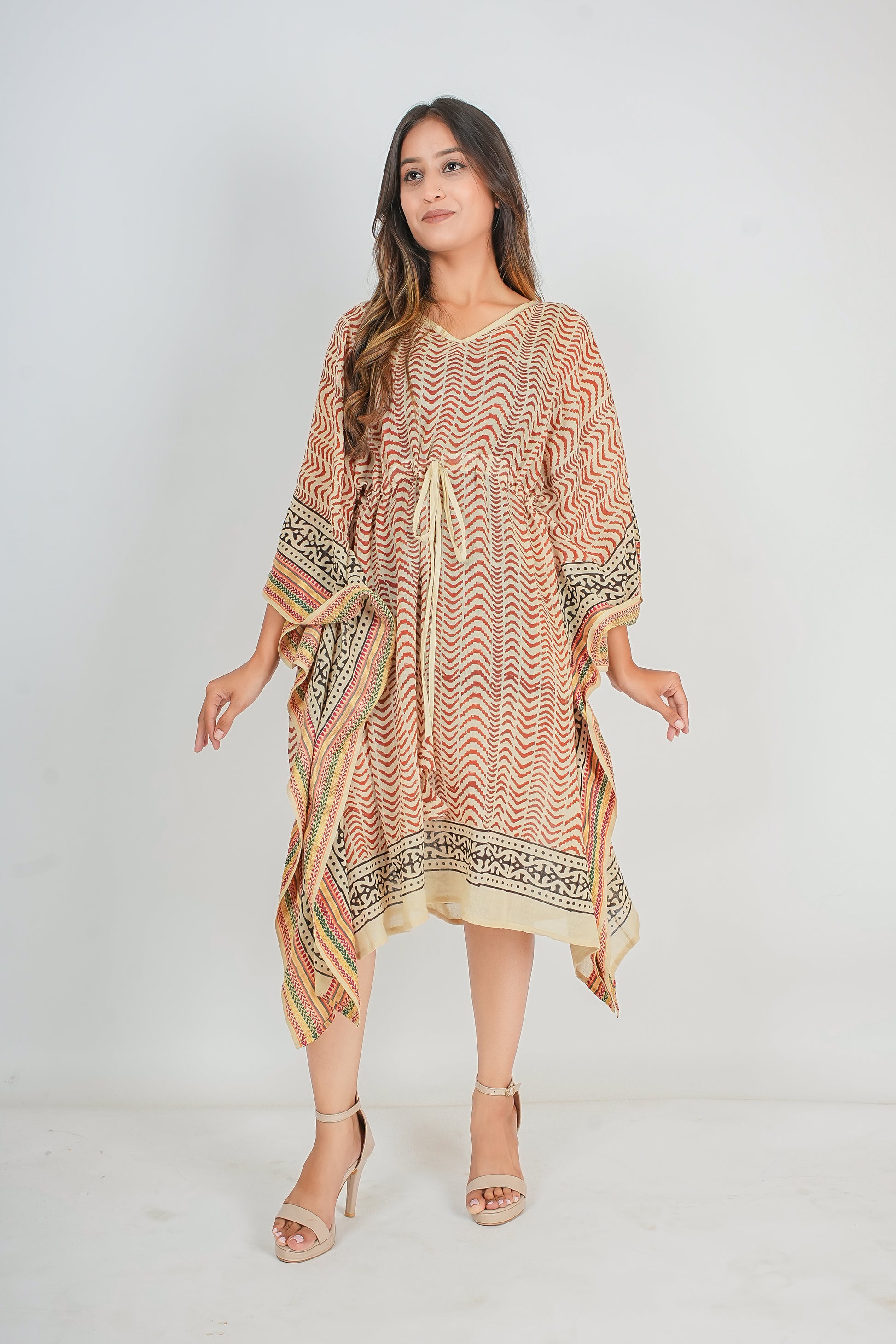 Woman wearing a patterned kaftan dress on a white background