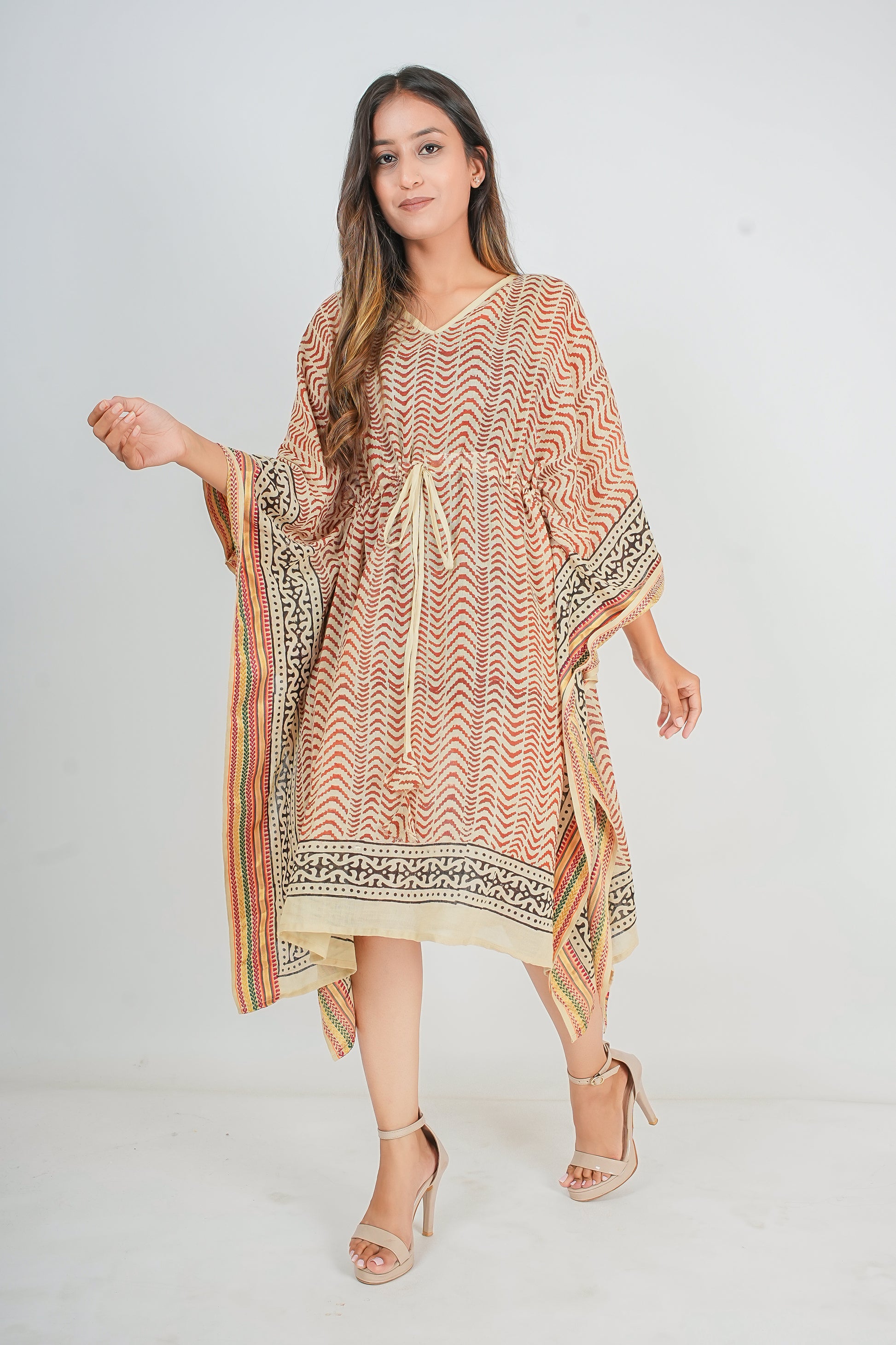 Woman wearing a patterned kaftan dress on a white background