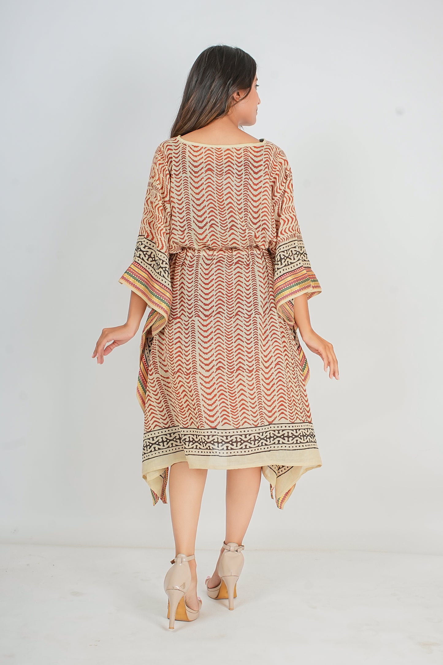 Woman wearing a patterned kaftan dress on a white background