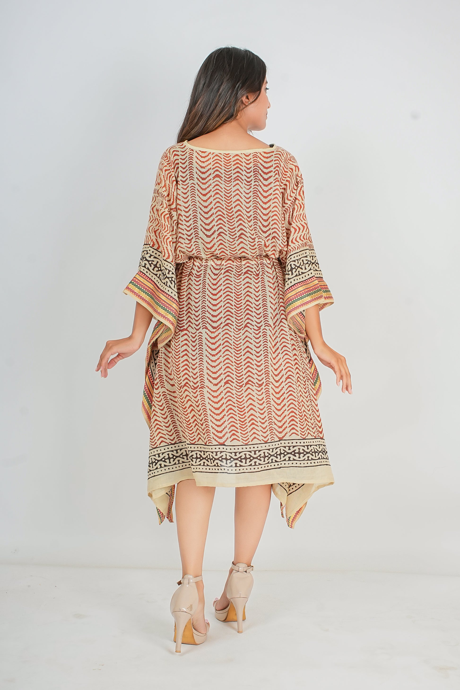 Woman wearing a patterned kaftan dress on a white background