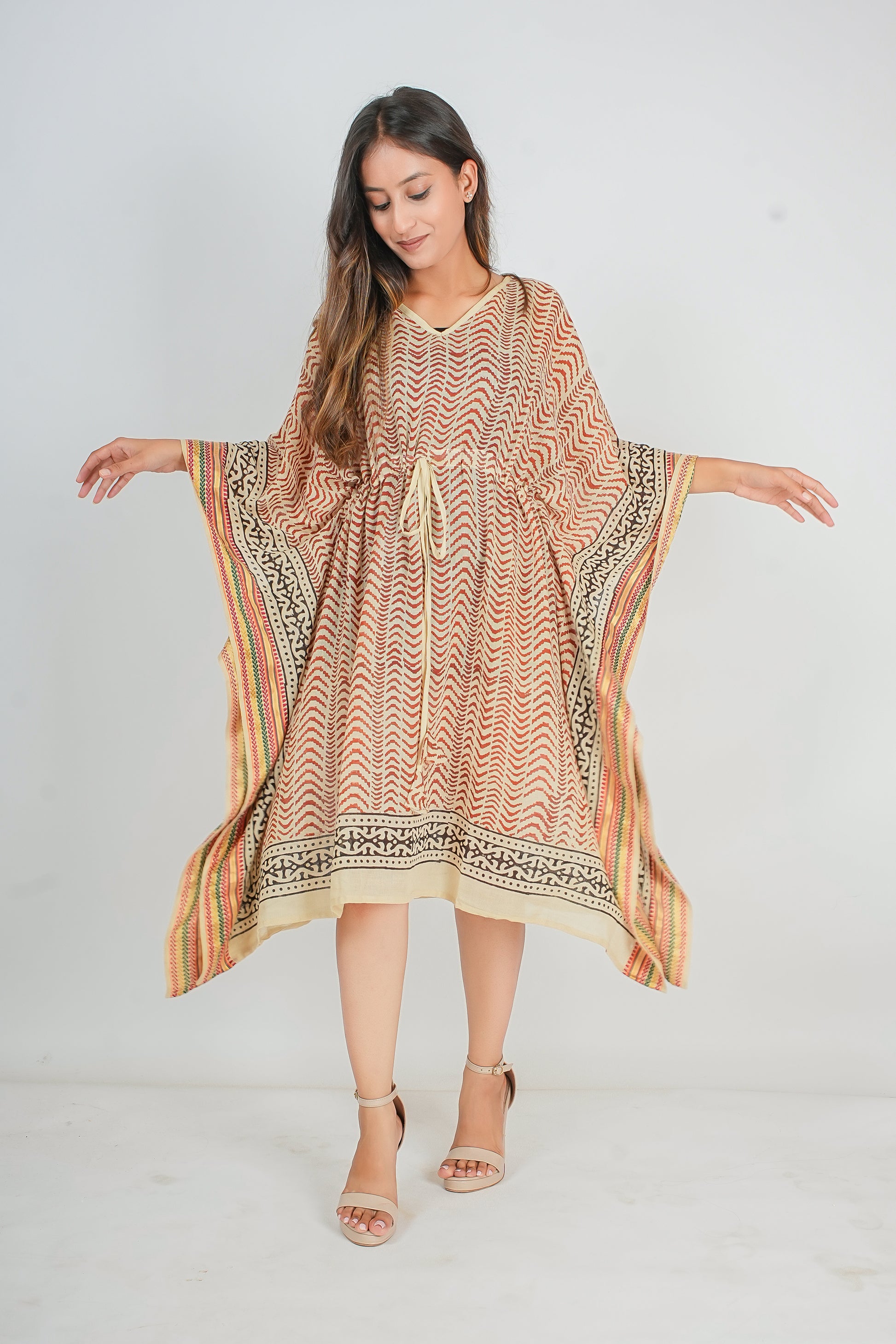 Woman wearing a patterned caftan dress on a white background