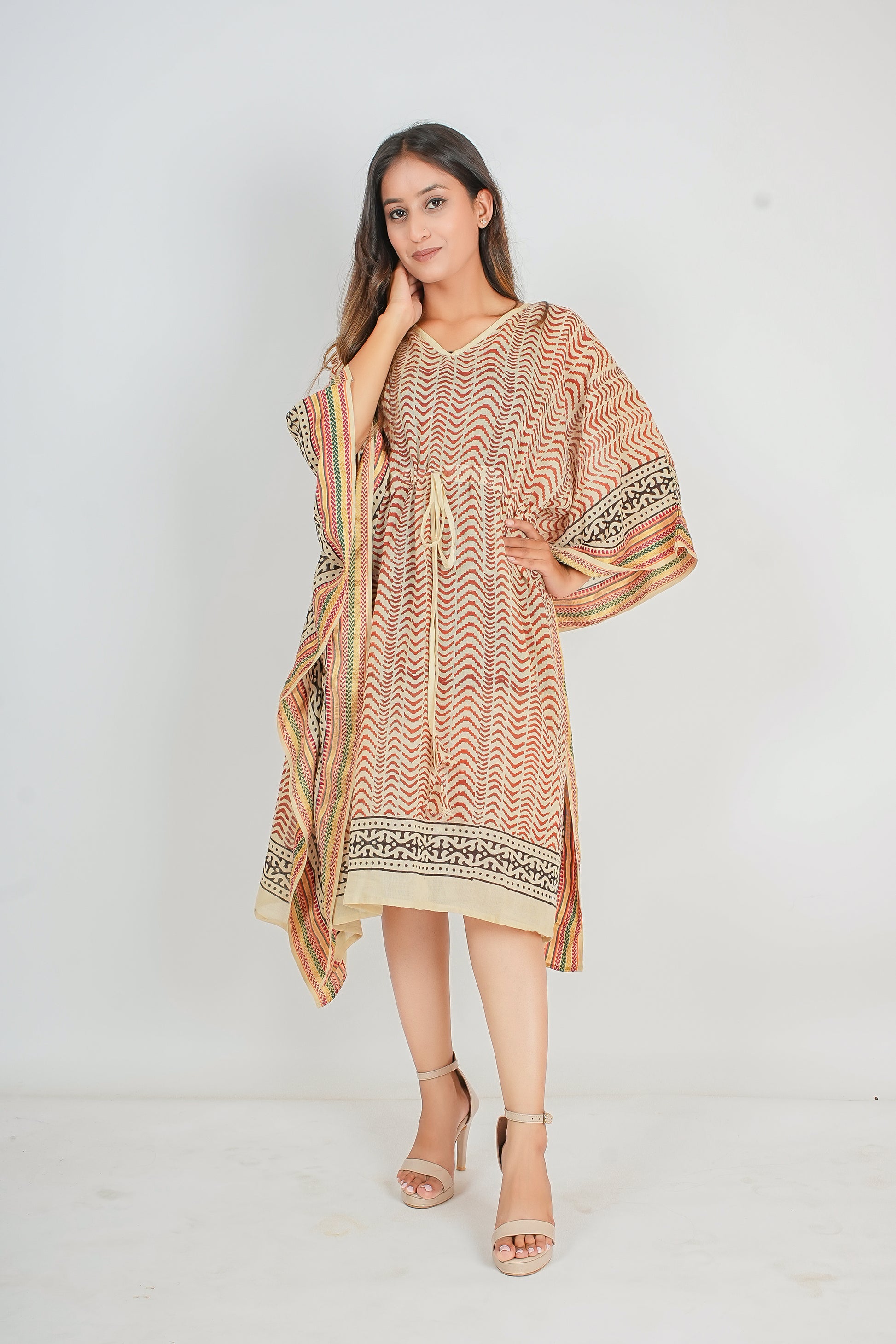 Woman wearing a patterned kaftan dress with a matching scarf on a white background